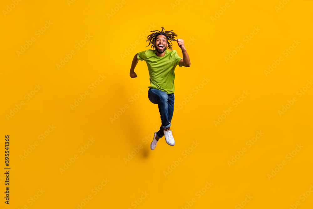 Full length photo portrait of man running forward laughing jumping up isolated on vivid yellow colored background Full length photo portrait of man running forward laughing jumping up isolated on vivid yellow colored background