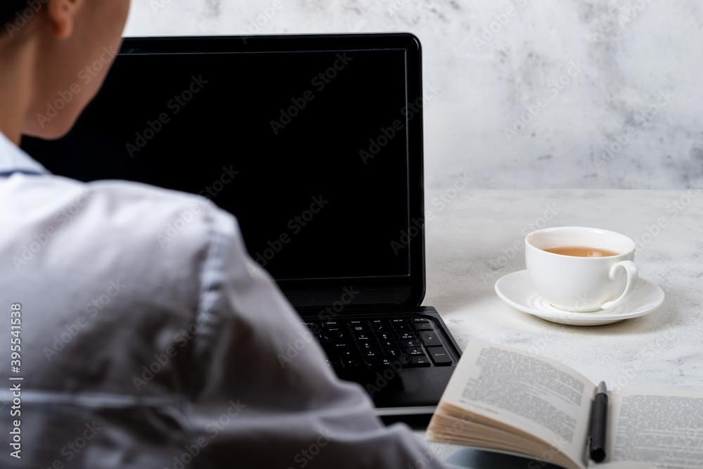 Fototapeta premium Girl sitting in front of laptop with a blank screen. Online education concept.