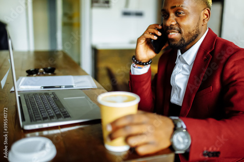 african american man getting online education and drinks coffee to go frop paper eco cup photo