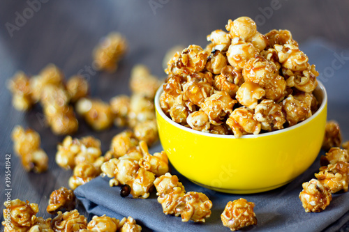 A close-up shot of golden caramel popcorn selective focus made from corn in a yellow bowl is a delicious gourmet crunchy snack food or snack for a homemade or entertaining movie.