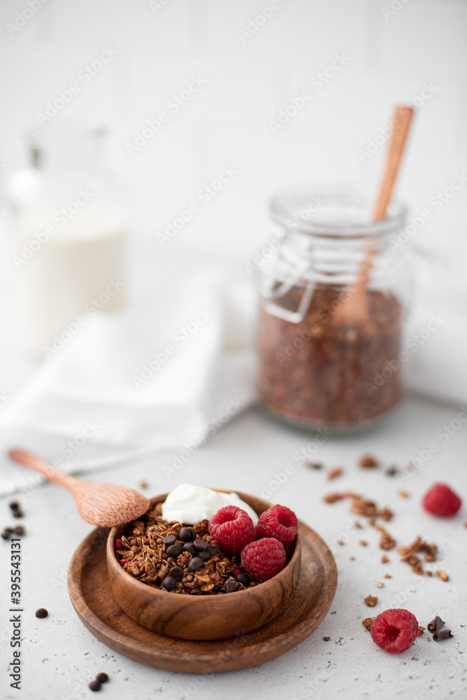 chocolate granola with greek yogurt and raspberries in a wooden bowl chocolate granola with greek yogurt and raspberries in a wooden bowl