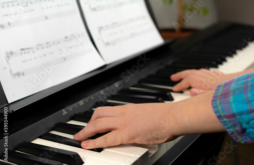 A child learns to play the piano in distance learning via a laptop over the Internet