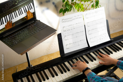 A child learns to play the piano in distance learning via a laptop over the Internet photo