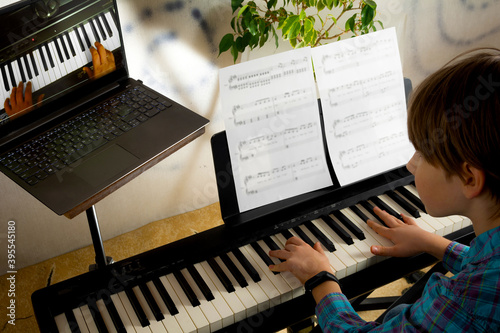 Boy learning to play the piano in distance learning via laptop over the Internet