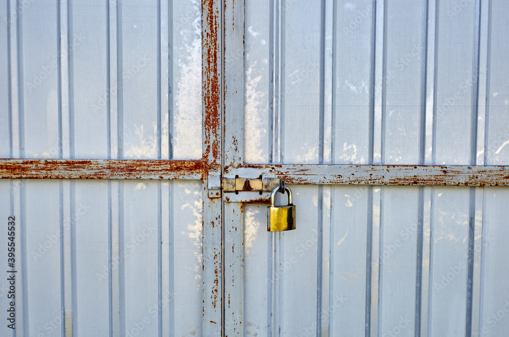 Iron rusty fence with a lock. White corrugated metal or zinc texture surface or galvanize steel in the vertical line background Iron rusty fence with a lock. White corrugated metal or zinc texture surface or galvanize steel in the vertical line background