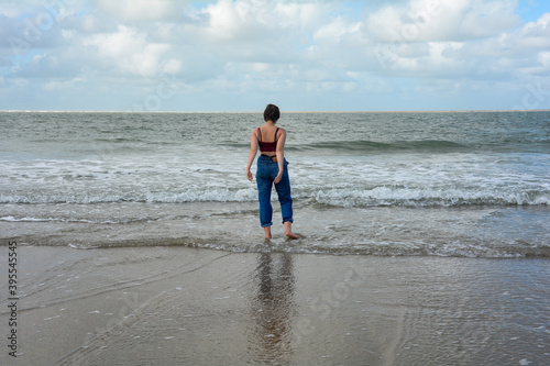 A woman playing with her feet with the water by the sea © Claudia Evans 