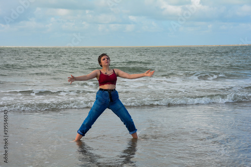 Young woman standing with open arms in the water by the sea