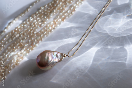 Natural baroque pearl pendant on a chain. Soft focus photo