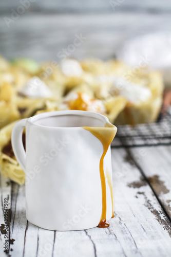 Sweet caramel sauce dripping from a white ceramic pitcher