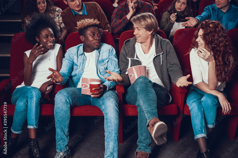 Obraz premium Two friends sit in front row at cinema and talk. 