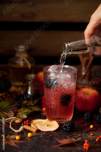 Pouring tonic water into an apple and blackberry gin and tonic photo