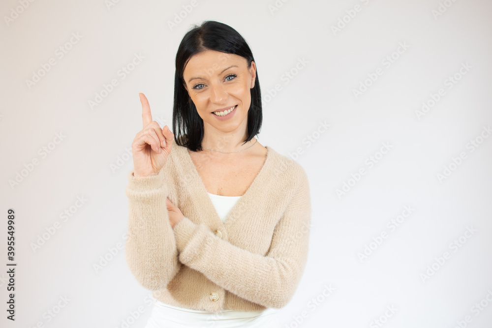 Young brunette woman with blue eyes wearing casual sweater over isolated white background pointing up with finger and raised arms. Young brunette woman with blue eyes wearing casual sweater over isolated white background pointing up with finger and raised arms.