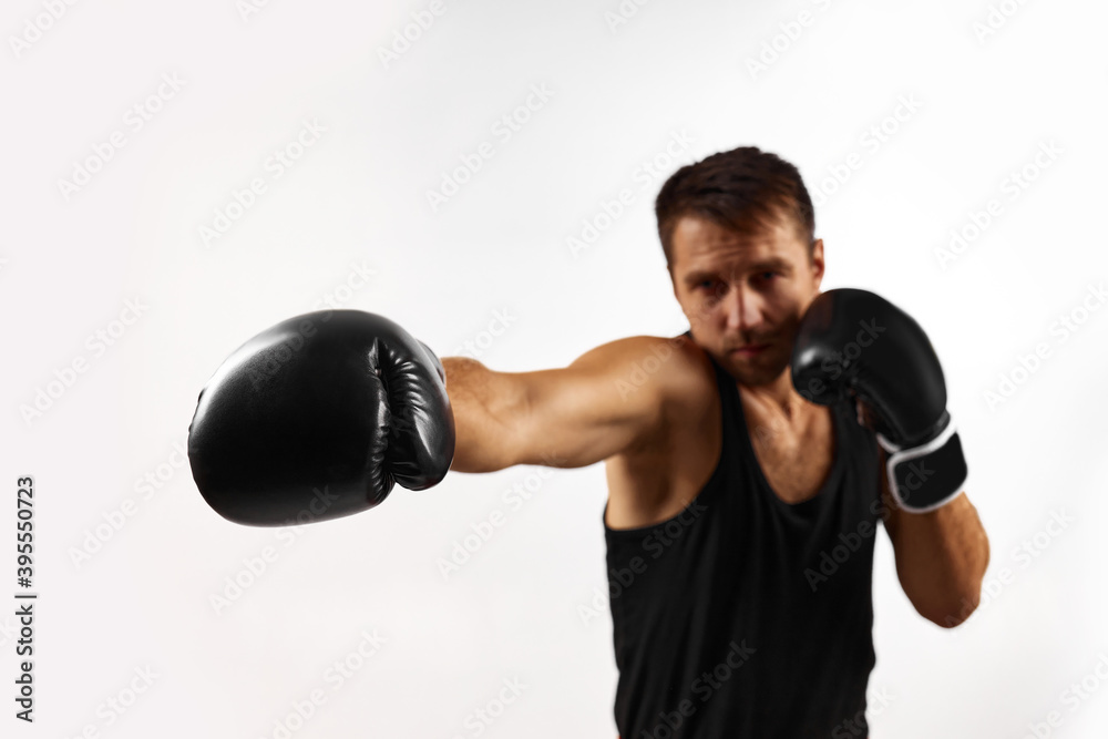 sporty man in black boxing gloves punching isolated on white background. focus on glove