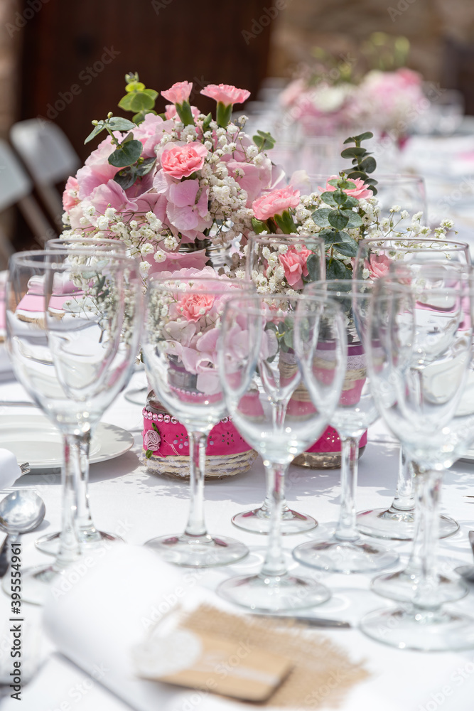 Wedding table decorated with bouquet of pink flowers and wine glasses.