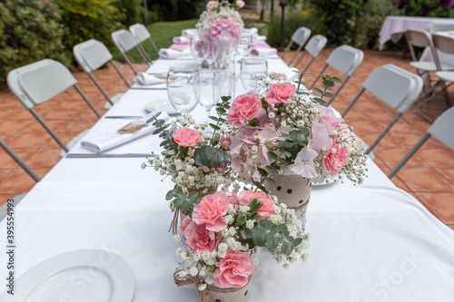 Wedding table decorated with bouquet of pink flowers and wine glasses.