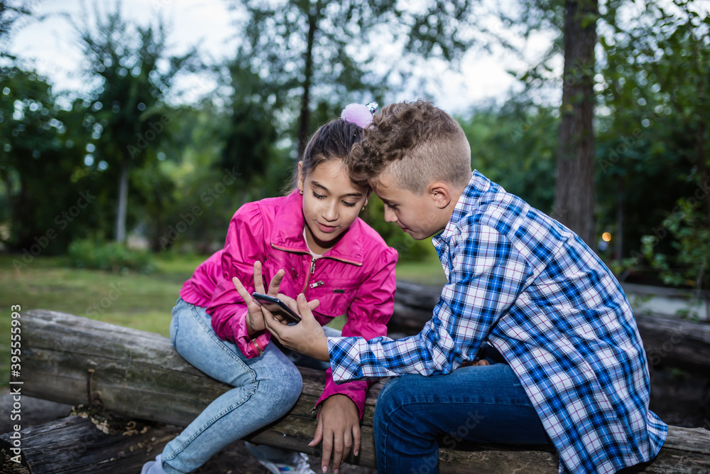 Happy smiling kids laughing and having fun while watching something funny on smart phone Happy smiling kids laughing and having fun while watching something funny on smart phone