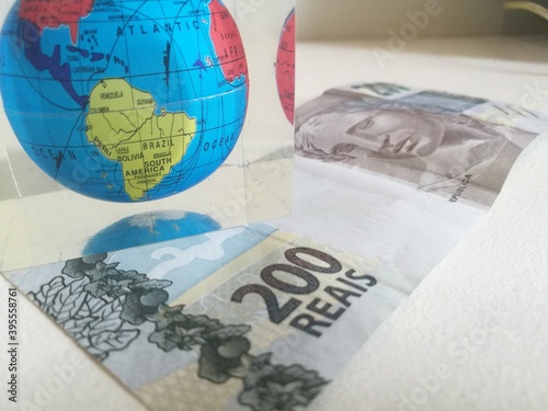 Brazilian 200 reais bank notes with the world globe on top. Maned Wolf on the currency. Two hundred real from Brazil. Close up of Brazilian money. New notes on moment of economic crisis on the planet. photo