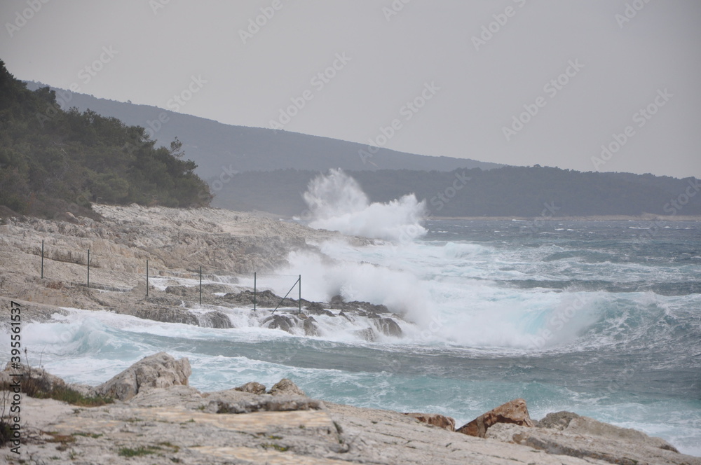 Storm with big waves and wind on the sea coast on the island of Losinj. Sea drops flood the shore and are carried by the wind