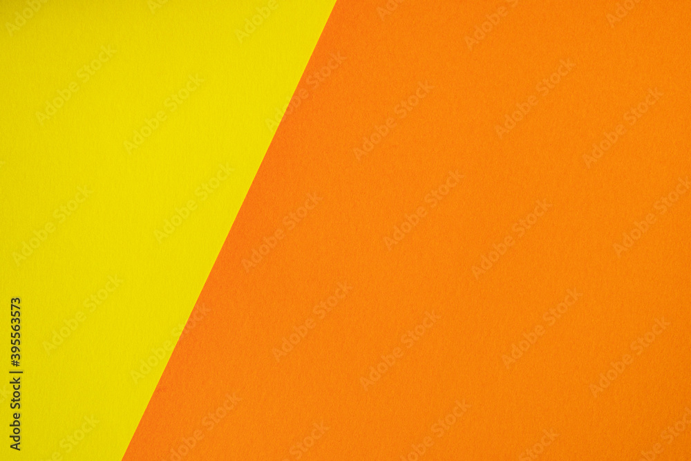Beautiful paper background of two unequal parts yellow and orange. Sheets of blank yellow and orange paper with fine texture separated by a sloping border.