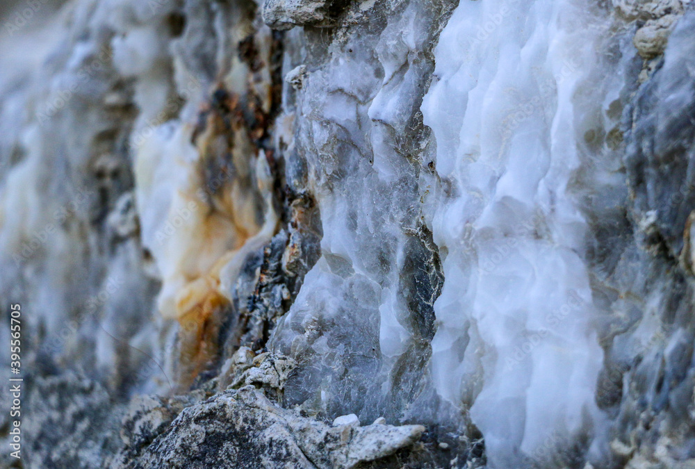 Diverse colored quartz rock in cut of the earth. Deposits of gray, white, orange quartz. Untreated semi-precious stones of chlatedony variety in various stone deposits and layers of different rocks. Diverse colored quartz rock in cut of the earth. Deposits of gray, white, orange quartz. Untreated semi-precious stones of chlatedony variety in various stone deposits and layers of different rocks.