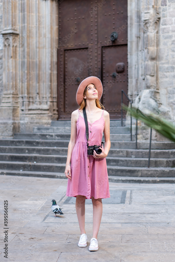 Woman tourist looking around and exploring the city. Solo female traveler holding a vintage camera in Barcelona Spain
