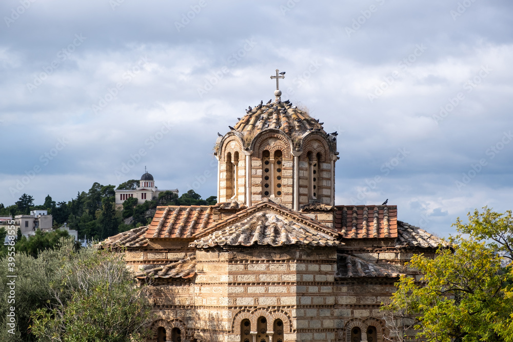 Greek Orthodox church in Thissio area, Athens, Greece. Flock of pigeons sitting on the dome, cloudy sky background Greek Orthodox church in Thissio area, Athens, Greece. Flock of pigeons sitting on the dome, cloudy sky background
