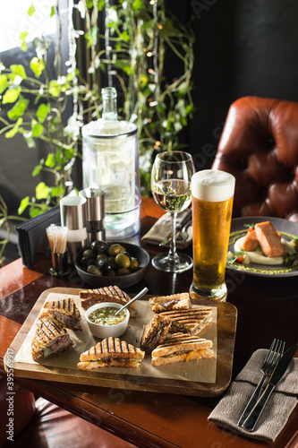 smoked meat sandwich and glass of beer on wooden table at restaurant