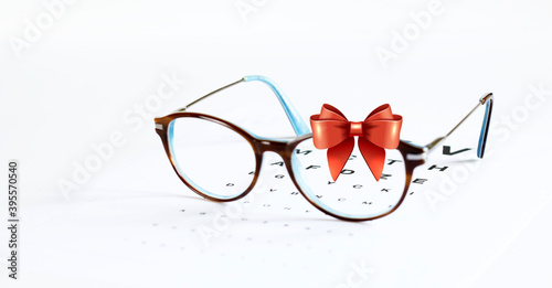 Occhiali da vista e fiocco in nastro rosso isolato su sfondo bianco. Carta regalo occhiali da vista di Natale. photo