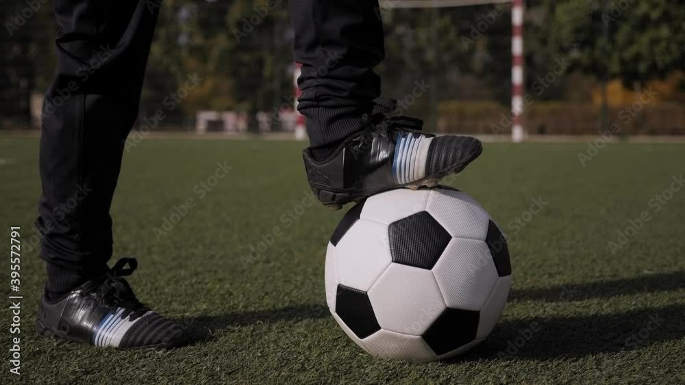 Close-up of a soccer ball on a field with green grass, a little boy puts his foot on the ball. Children's sports Concept. Close-up of a soccer ball on a field with green grass, a little boy puts his foot on the ball. Children's sports Concept.