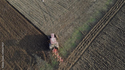 Birds eye view of a tractor starting to plough a row in a field. Drone static locked off shot. photo