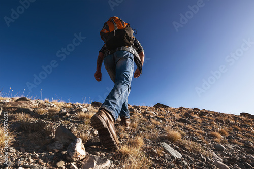 Unrecognizable male traveler goes uphill photo