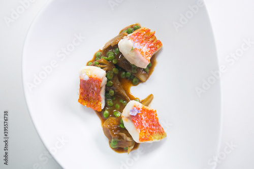 Grilled striped red mulled with artichokes and peas. photo