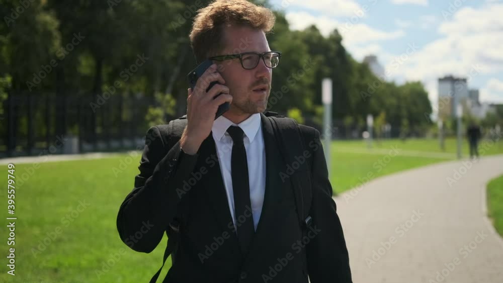 Office worker talking on cellphone outdoors, electric scooter nearby Office worker talking on cellphone outdoors, electric scooter nearby