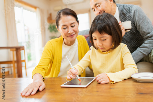 タブレット学習をする孫を見守る祖父母