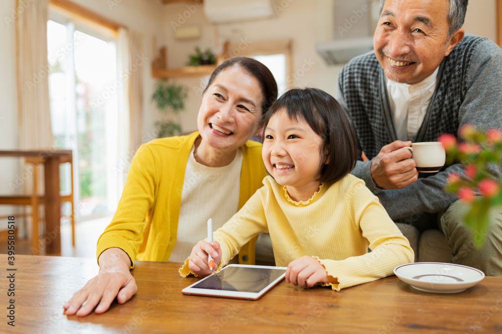 タブレット学習をする孫を見守る祖父母 タブレット学習をする孫を見守る祖父母
