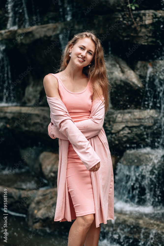 Young woman in pink dress posing near blurred waterfall. Kuala Lumpur. Malaysia Young woman in pink dress posing near blurred waterfall. Kuala Lumpur. Malaysia