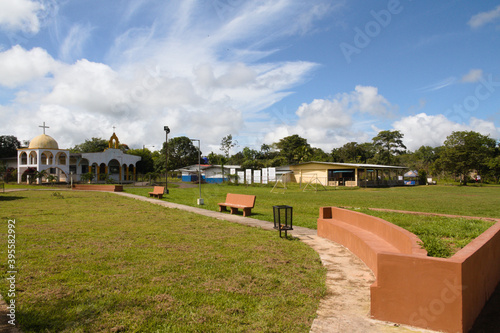 village park with green areas, kiosk and church on a sunny day photo