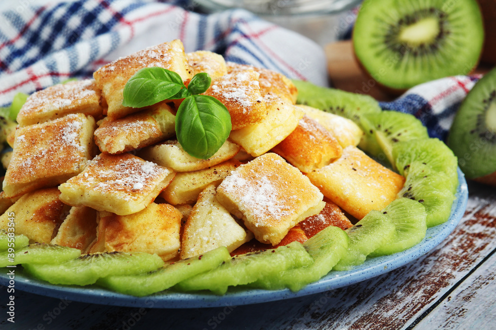 Austrian dessert Kaiserschmarrn served with sugar powder and kiwi fruit Austrian dessert Kaiserschmarrn served with sugar powder and kiwi fruit