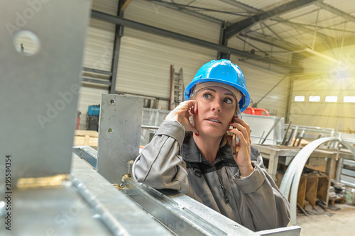 Woman worker is calling on her phone in the workshop © ElitProd