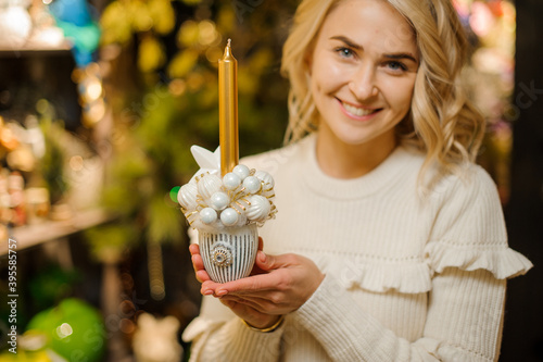 lovely composition in pot of white Christmas balls and golden candle in hands of woman