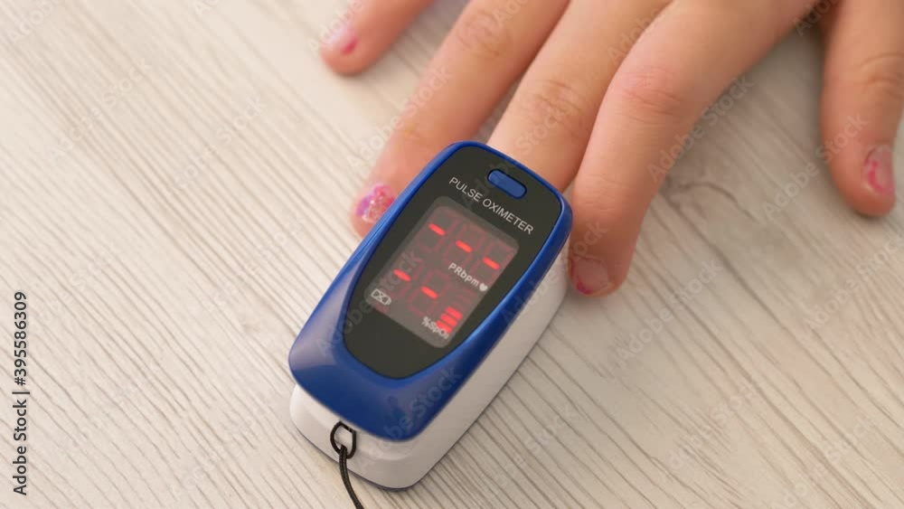 Adult woman sticks her finger into a pulse oximeter. A girl checks the pulse and oxygen level in the blood during the corona virus pandemic. Diagnostics of covid-19 Adult woman sticks her finger into a pulse oximeter. A girl checks the pulse and oxygen level in the blood during the corona virus pandemic. Diagnostics of covid-19