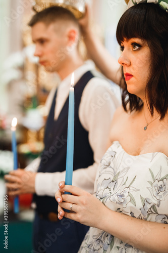 Bride and groom holding candles in church photo