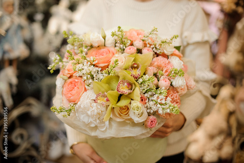 Great flower arrangement of fresh orchids  roses  peonies and white lilacs in hands of woman.