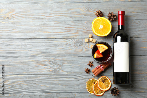 Foto Bottle of wine, cup of mulled wine and ingredients on wooden background