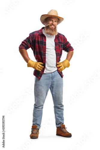 Full length portrait of a bearded farmer with gloves and a straw hat