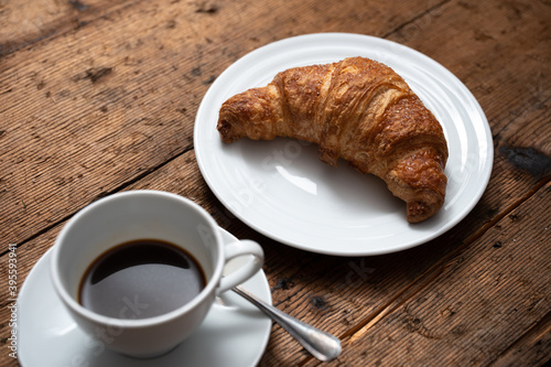 breakfast on wooden table with croissants and cup of coffee