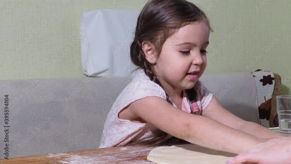 Cute little girl and her beautiful mom are playing and laughing while kneading the dough in the kitchen. Cute little girl and her beautiful mom are playing and laughing while kneading the dough in the kitchen.