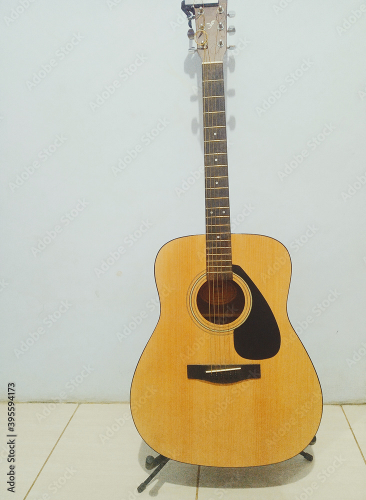 Naklejka premium Acoustic guitar coloured yellow on the background white