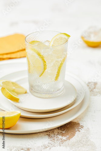 A glass of water with ice cubes and lemon wedges