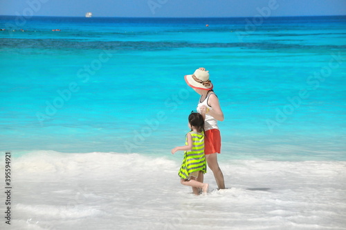 Mother and daughter are walking hand in hand to the beautiful beach. 